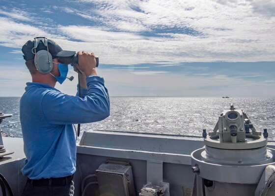 Seaman Zachery Douglas, from Dansville, N.Y., looks through binoculars on the bridge as the Arleigh Burke-class guided-missile destroyer USS Mustin (DDG 89) conducts routine operations.