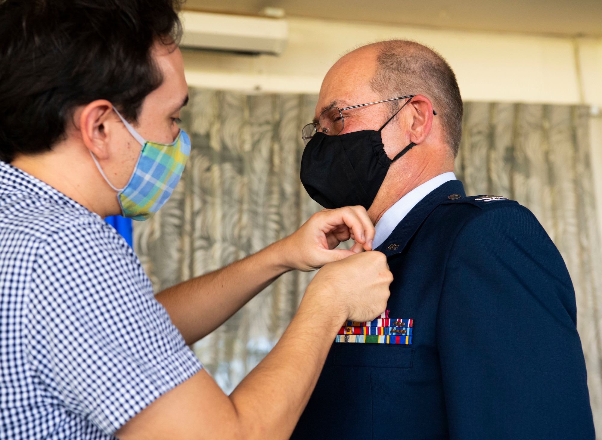 A photo of David Bradshaw presenting a retirement pin to his father, U.S. Air Force Col. Lee Bradshaw, the former commander of the 624th Aeromedical Staging Squadron, during his retirement ceremony at Joint Base Pearl Harbor-Hickam, Hawaii, Aug. 9, 2020.