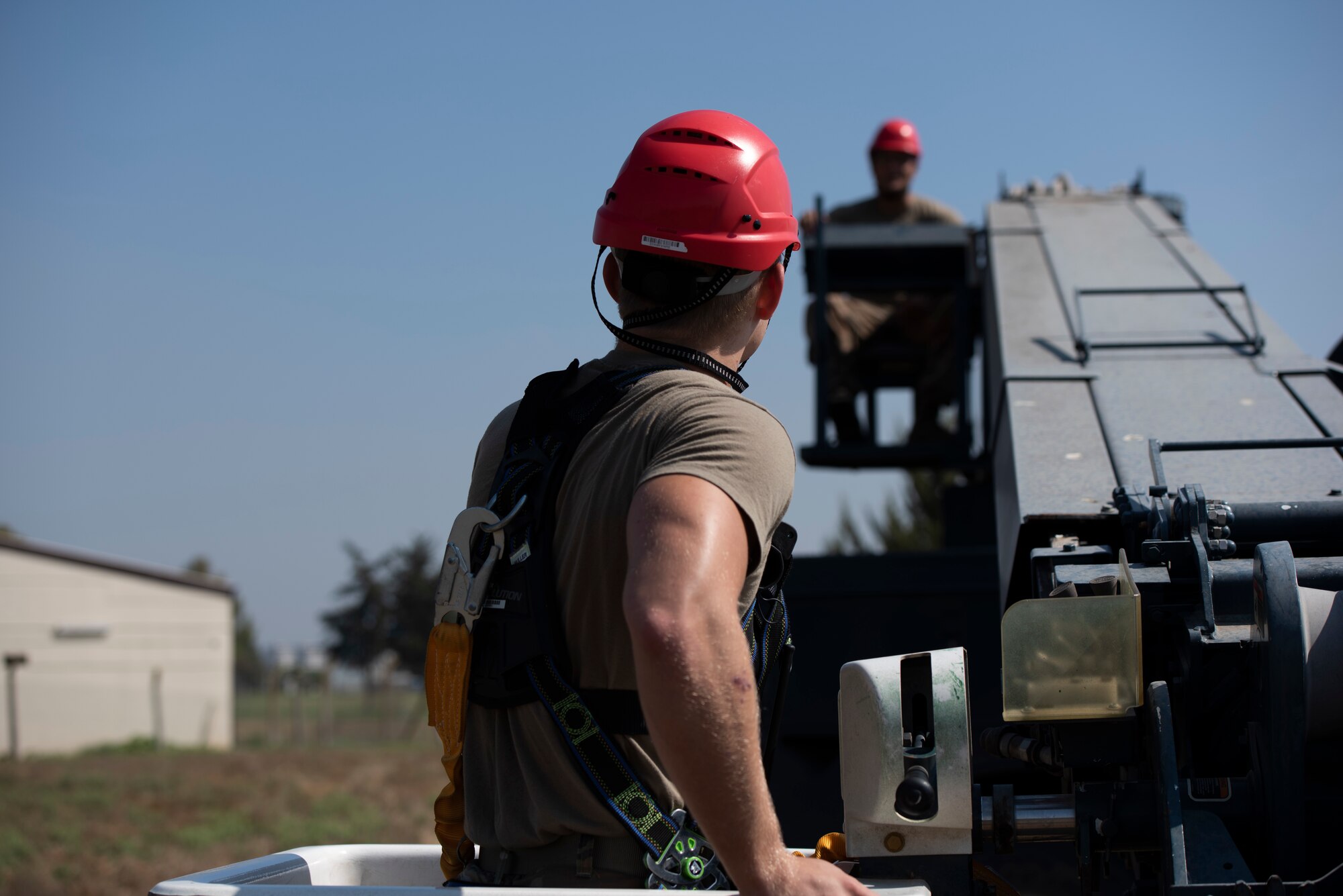 U.S. Senior Airmen Noah Dray climbs into a bucket lift while Senior Airman Tyler McNaughton operates the controls at Incirlik Air Base, August 12, 2020.