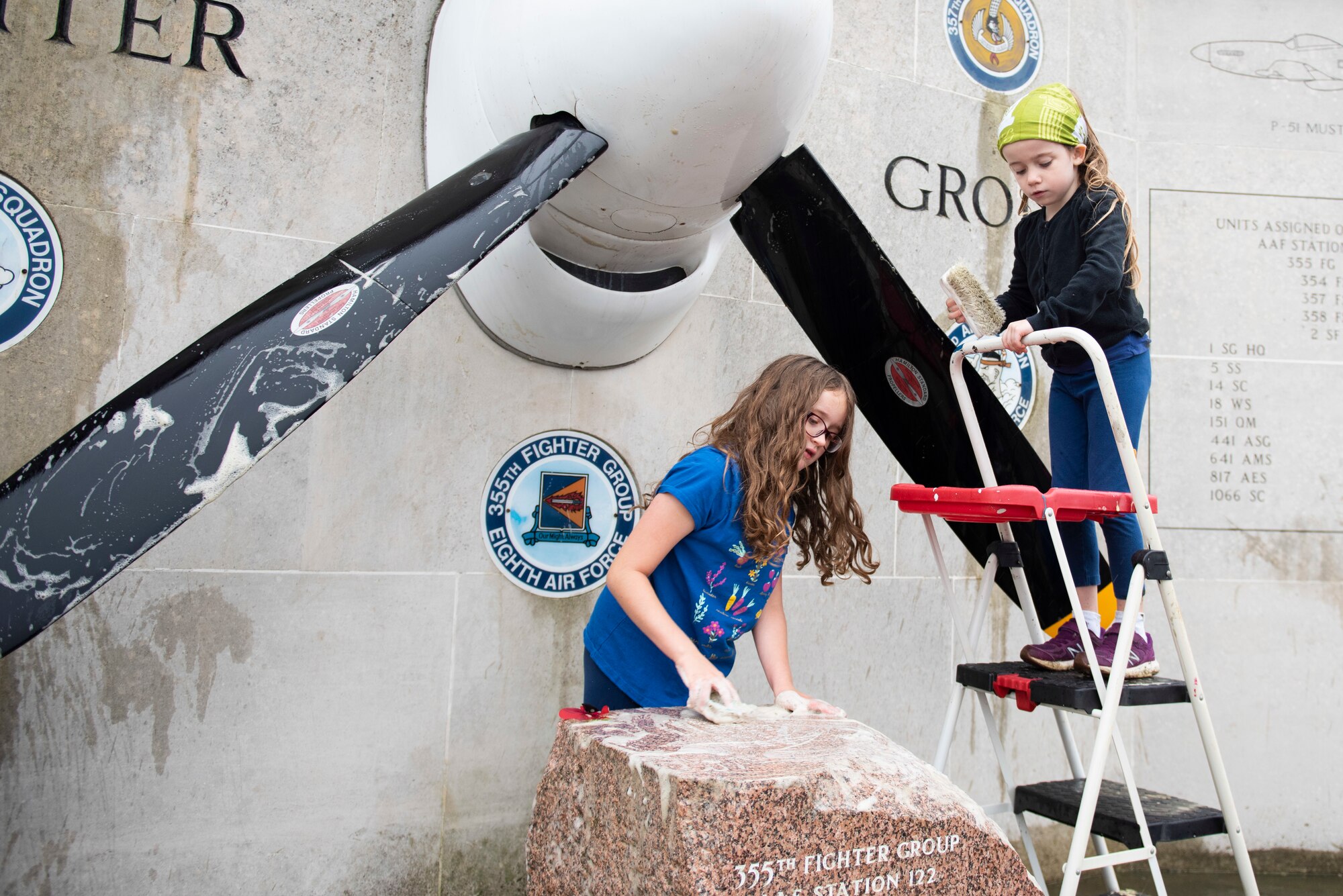 Jessa and Kaitlyn Dunmire scrub the 355th Fighter Group Steeple Morden Memorial in Steeple Morden, England, during Operation TORCH-2020 memorial cleanup August 15, 2020. U.S. Africa Command Directorate for Intelligence at RAF Molesworth partnered with the American Battle Monuments Commission to host Operation TORCH-2020, where over 50 military members and their families, U.K. nationals and Boy Scout Troop #245, cleaned six WWII memorial sites to preserve American service member legacies and promote an appreciation of past American heroes among present-day USAFRICOM workforce and families. (U.S. Air Force Photo by Airman 1st Class Jennifer Zima)