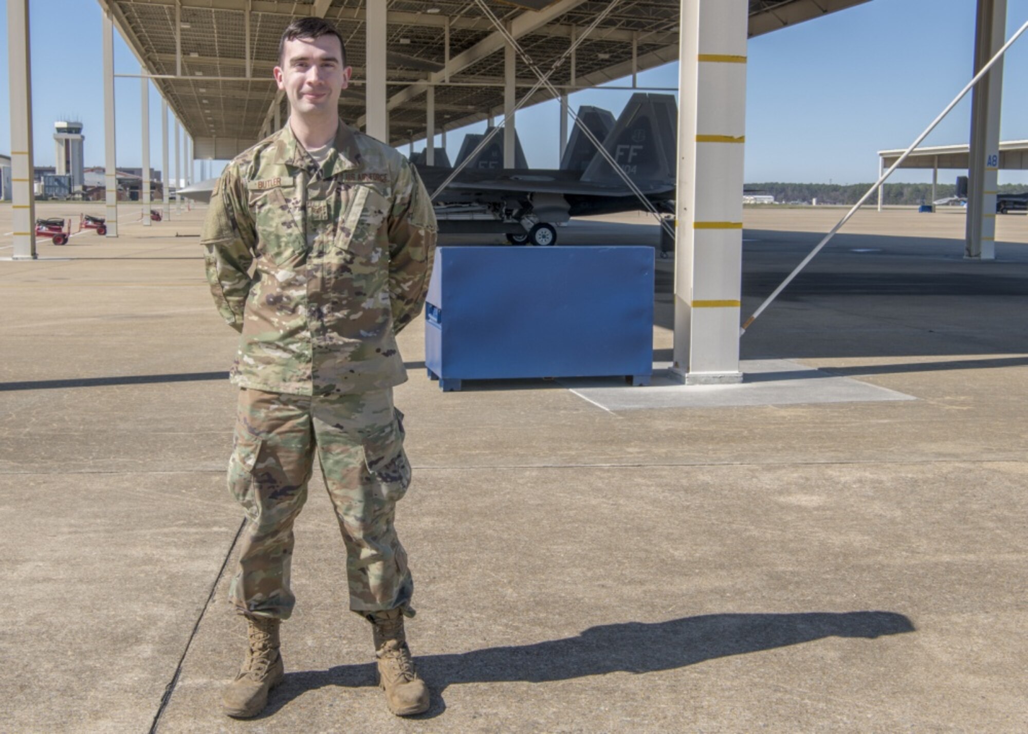 An Airman stands on the flight line in front of F-22 aircraft