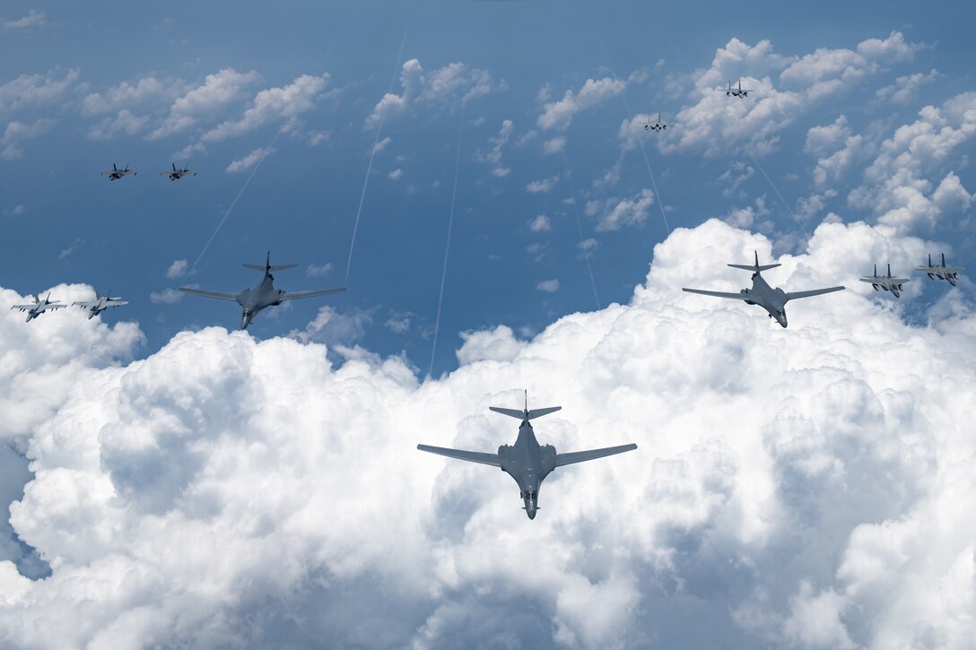 Military aircraft fly together above the clouds.