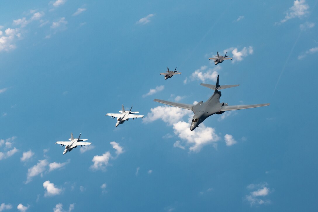 Five military aircraft fly together.