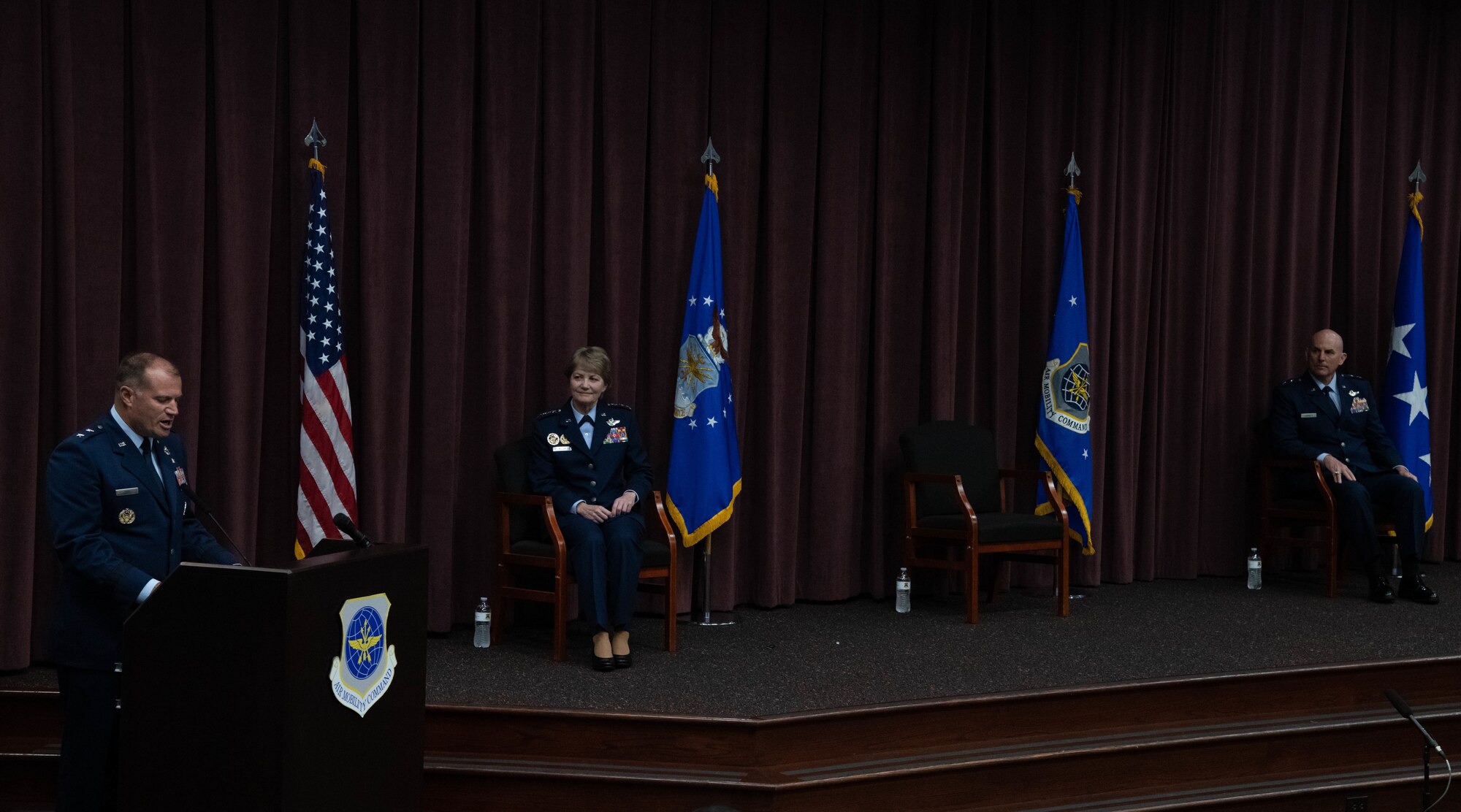 Maj. Gen. Bibb delivers remarks at podium while Gen. Maryanne Miller and Maj. Gen. Barrett view from the stage.