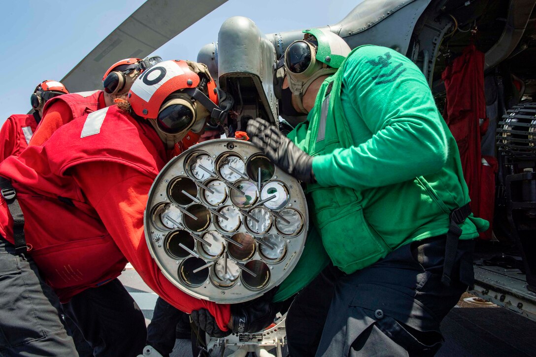 Sailors load missiles onto a helicopter.