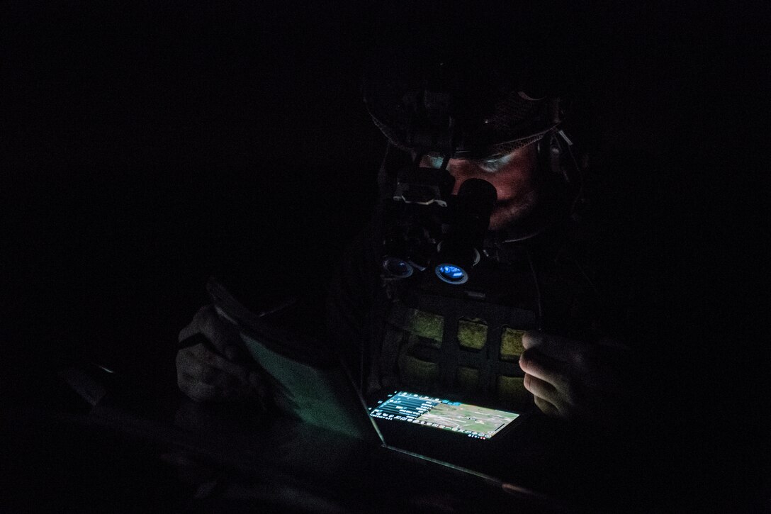 A special operations troop works at night with only his head and shoulders dimly lit by his tablet. The troop prepares to conduct close air support during the Special Operations Terminal Attack Controller Course at Avon Park Florida, Aug. 6, 2020.