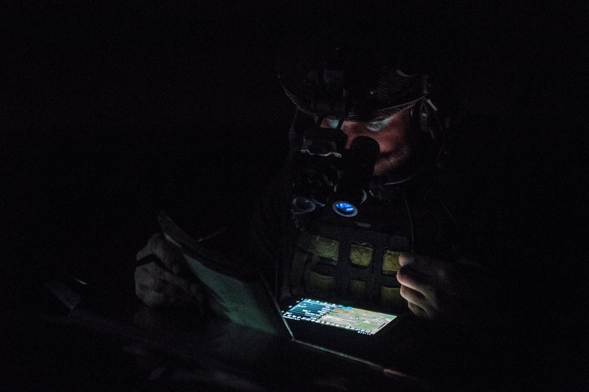 A special operations troop works at night with only his head and shoulders dimly lit by his tablet. The troop prepares to conduct close air support during the Special Operations Terminal Attack Controller Course at Avon Park Florida, Aug. 6, 2020.