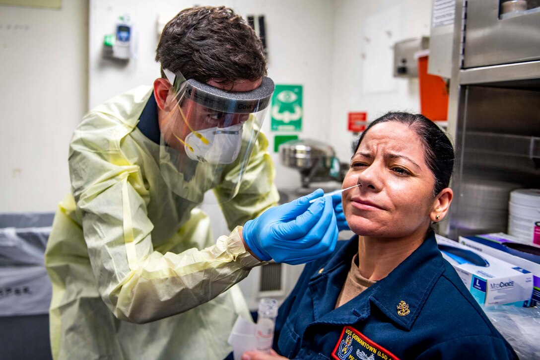 A sailor tests another sailor for COVID-19.