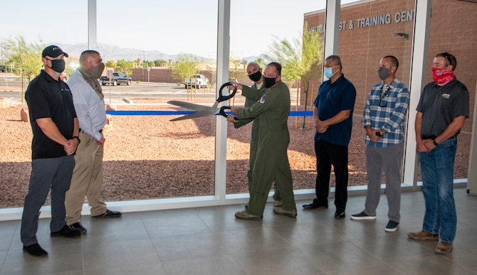 Airmen and civilians stand outside the  grad opening of the U.S. Warfare Center Virtual Test and Training Center to cut a ribbon.