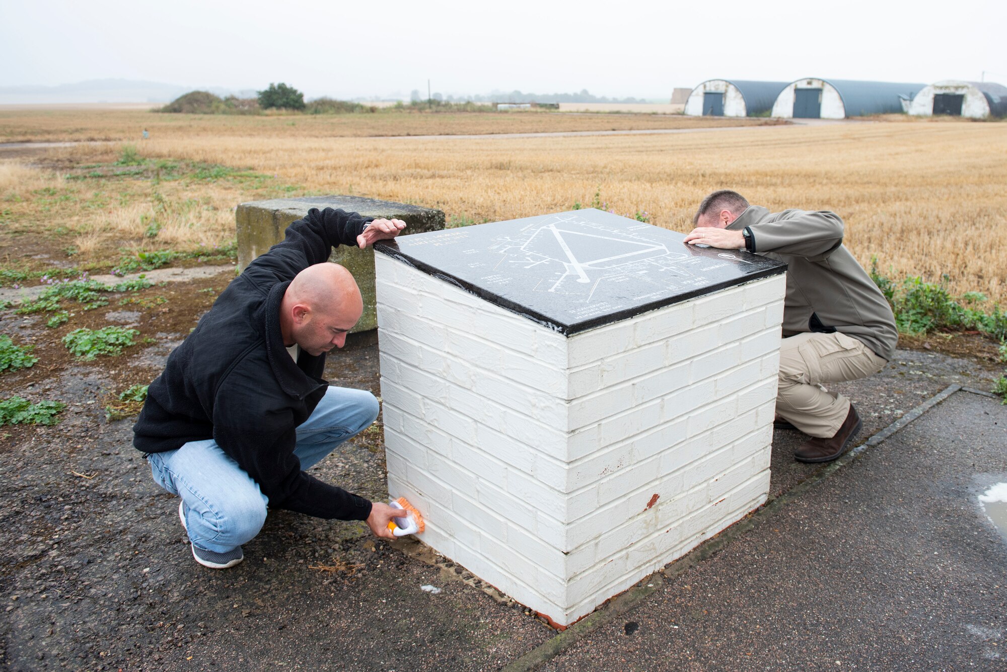 U.S. Air Force Tech. Sgt. Manuel III Minjarez, U.S. Africa Command Directorate for Intelligence at RAF Molesworth technician, scrubs the 355th Fighter Group Steeple Morden Memorial in Steeple Morden, England, during Operation TORCH-2020 memorial cleanup August 15, 2020. U.S. Africa Command Directorate for Intelligence at RAF Molesworth partnered with the American Battle Monuments Commission to host Operation TORCH-2020, where over 50 military members and their families, U.K. nationals and Boy Scout Troop #245, cleaned six WWII memorial sites to preserve American service member legacies and promote an appreciation of past American heroes among present-day USAFRICOM workforce and families. (U.S. Air Force Photo by Airman 1st Class Jennifer Zima)