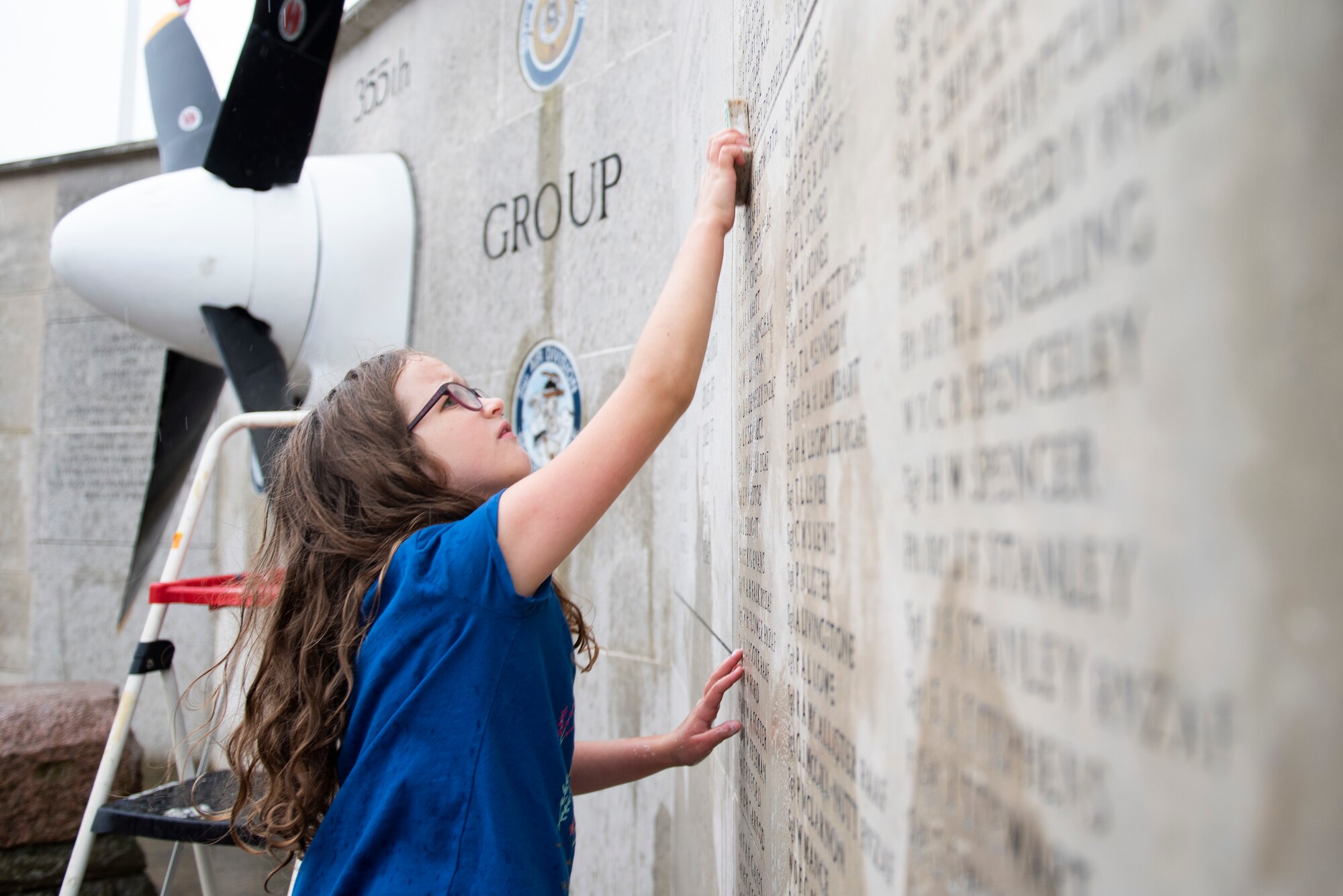 Jessa Dunmire scrubs the 355th Fighter Group Steeple Morden Memorial in Steeple Morden, England, during Operation TORCH-2020 memorial cleanup August 15, 2020. U.S. Africa Command Directorate for Intelligence at RAF Molesworth partnered with the American Battle Monuments Commission to host Operation TORCH-2020, where over 50 military members and their families, U.K. nationals and Boy Scout Troop #245, cleaned six WWII memorial sites to preserve American service member legacies and promote an appreciation of past American heroes among present-day USAFRICOM workforce and families. (U.S. Air Force Photo by Airman 1st Class Jennifer Zima)