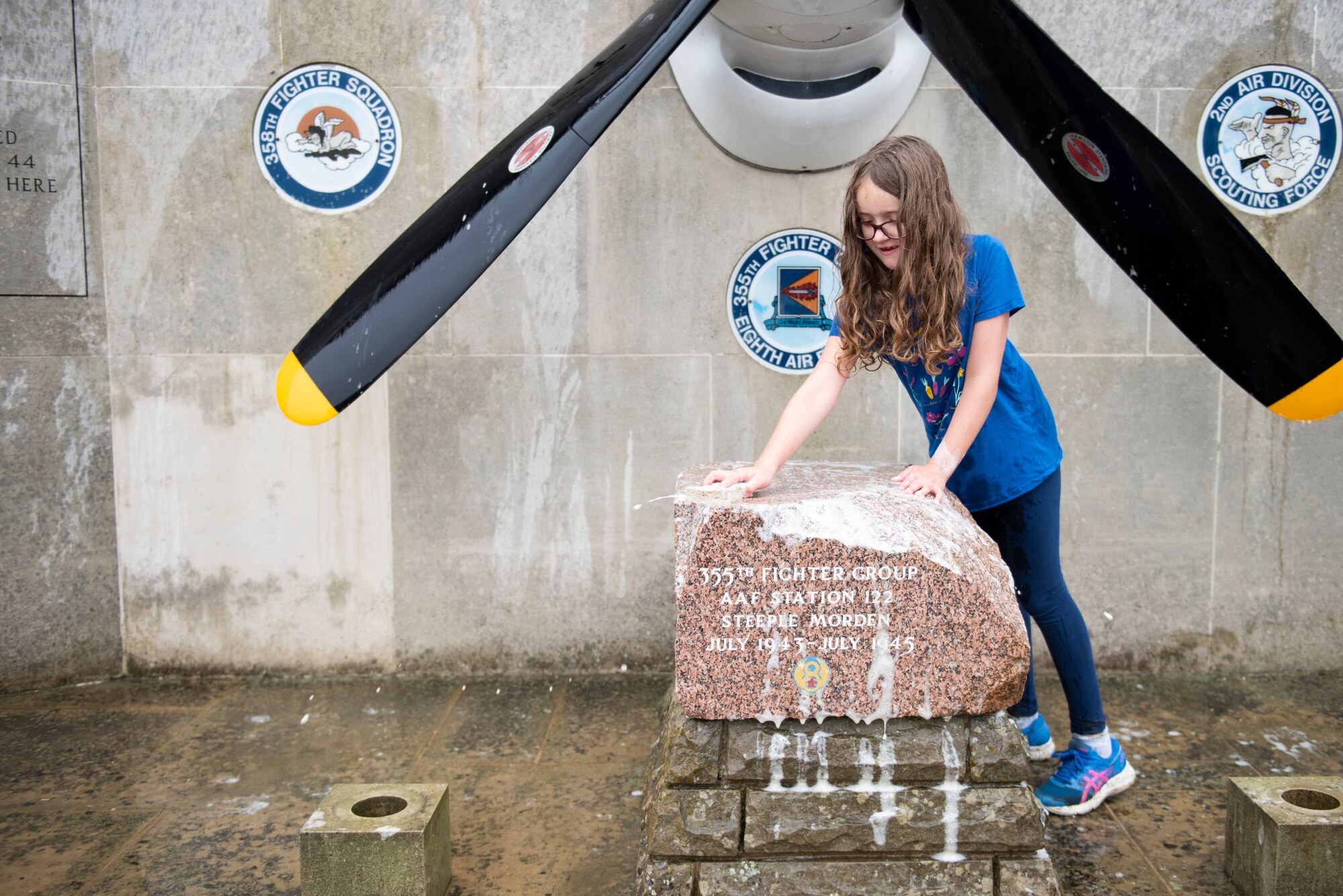 Jessa Dunmire scrubs the 355th Fighter Group Steeple Morden Memorial in Steeple Morden, England, during Operation TORCH-2020 memorial cleanup August 15, 2020. U.S. Africa Command Directorate for Intelligence at RAF Molesworth partnered with the American Battle Monuments Commission to host Operation TORCH-2020, where over 50 military members and their families, U.K. nationals and Boy Scout Troop #245, cleaned six WWII memorial sites to preserve American service member legacies and promote an appreciation of past American heroes among present-day USAFRICOM workforce and families. (U.S. Air Force Photo by Airman 1st Class Jennifer Zima)