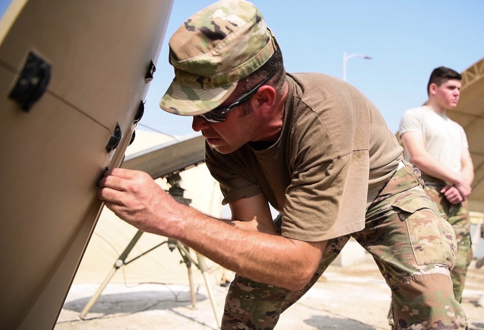 Tech. Sgt. Stephen Langdon (foreground), a member of the 380th Expeditionary Communications Squadron, connects segments of the Hawkeye 1.2 meter carbon fiber reflector dish Aug. 19, 2020 at Al Dhafra Air Base, United Arab Emirates, while Airman Chandler Harward looks on (background).