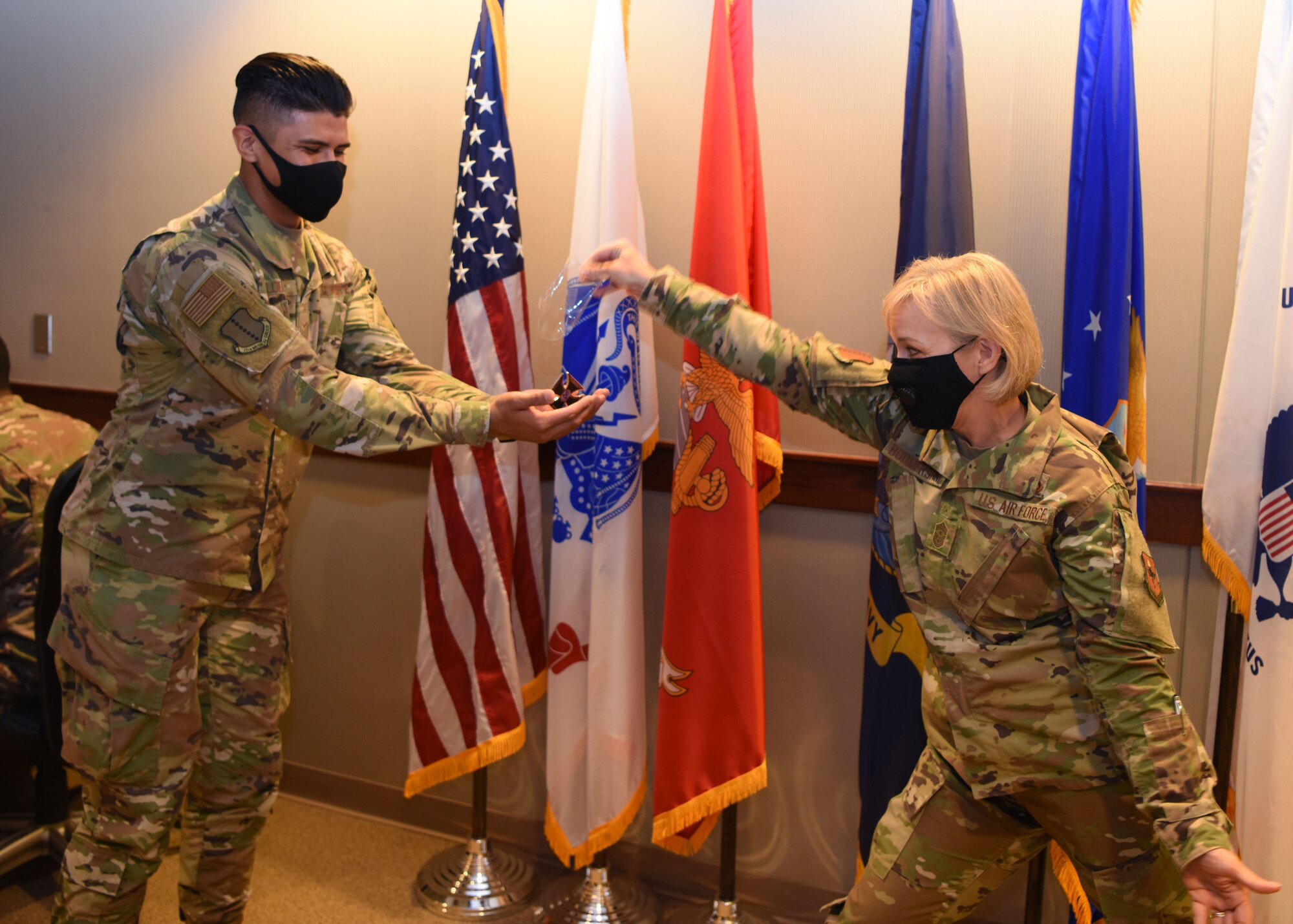 U.S. Air Force Chief Master Sgt. Casy Boomershine, 17th Training Wing command chief, presents a coin to Airman 1st Class Benjamin Medina-Loera, 17th Operational Medical Readiness Squadron aerospace medical technician, for his outstanding performance in his field at Norma Brown on Goodfellow Air Force Base, Texas, Aug. 18, 2020. Medina-Loera assisted the active duty population of Goodfellow and kept them mission ready. (U.S. Air Force photo by Airman 1st Class Ethan Sherwood)