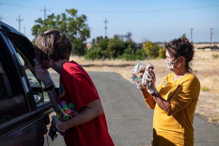 Blair Downs, 9th Force Support Squadron (FSS) marketing director talks to the driver of a car while Cathy Rodgers, 9th FSS marketing graphic designer, offers ice cream for the children in the back of the car on Beale Air Force Base.