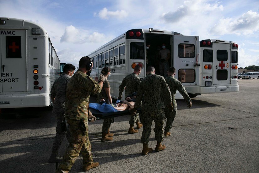 Airmen and Seamen move a patient into a medical transport bus at Joint Base Andrews, Md., Aug. 13, 2020. Medical staff work together with other units and services to ensure they provide the best quality care possible for patients. (U.S. Air Force photo by Airman 1st Class Spencer Slocum)
