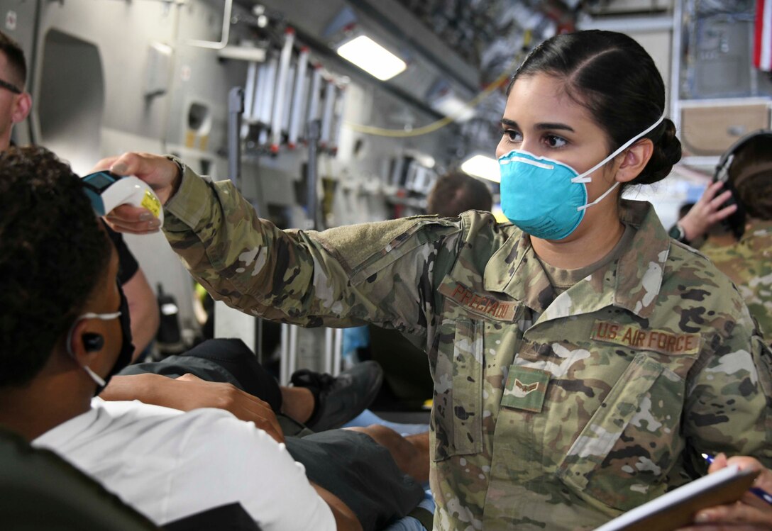 Airman 1st Class Gabriela Preciado, 11th Surgical Operations Squadron medical technician, takes the temperature of a patient at Joint Base Andrews, Md., Aug. 13, 2020. Protocols such as taking patients’ temperatures and verifying their identities are mandatory before patients can be offloaded from the aircraft. (U.S. Air Force photo by Airman 1st Class Spencer Slocum)