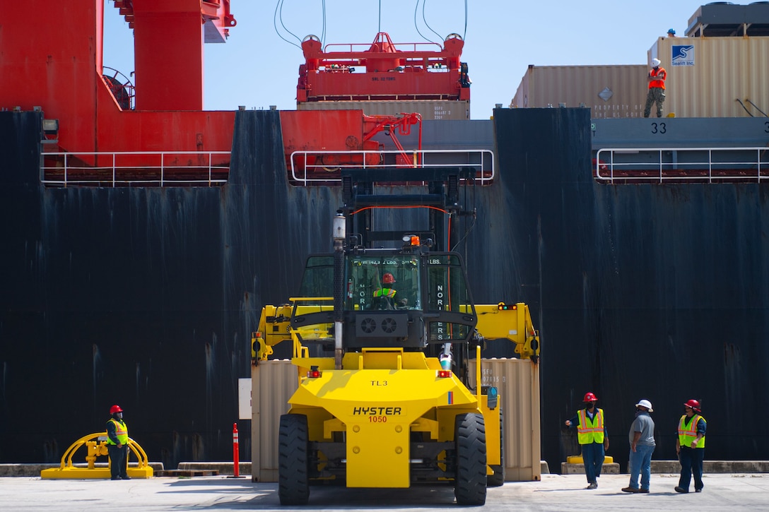 Large containers are placed on a ship.