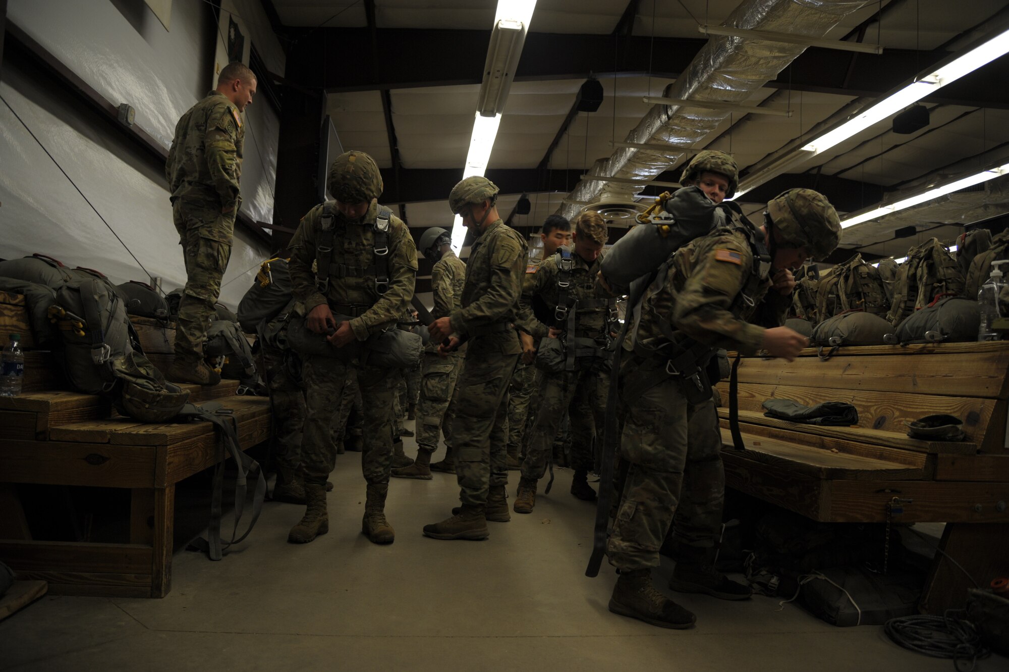 paratroopers put on their required equipment to jump from an aircraft