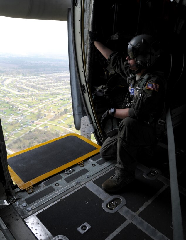 a man kneels looking our of an aircraft