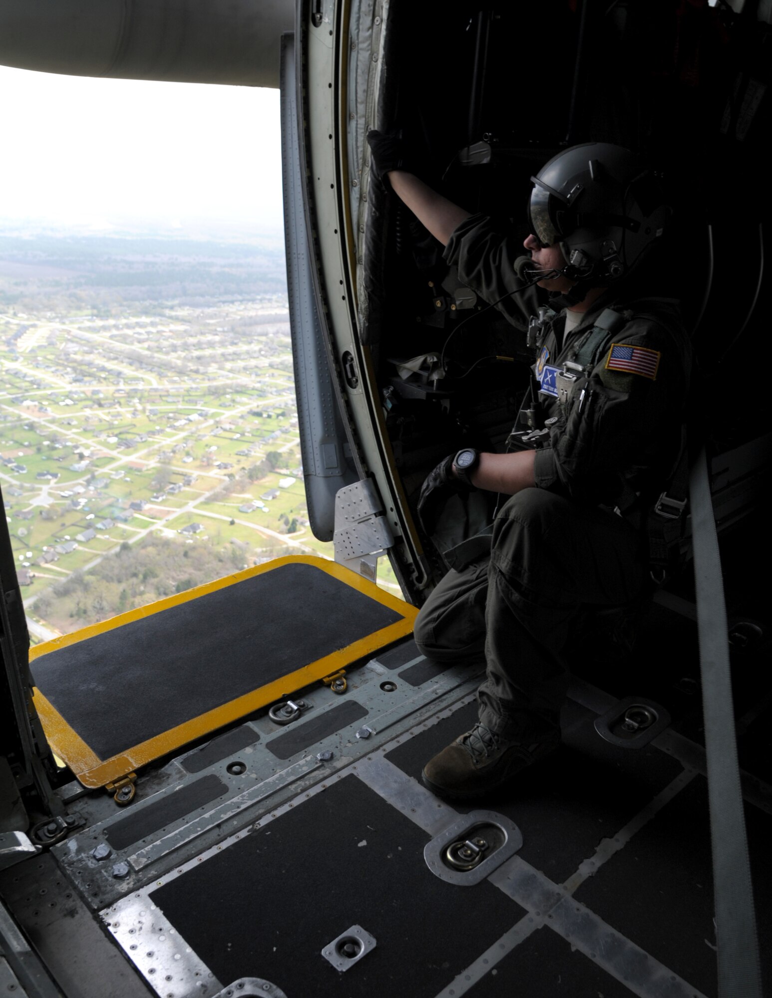 a man kneels looking our of an aircraft