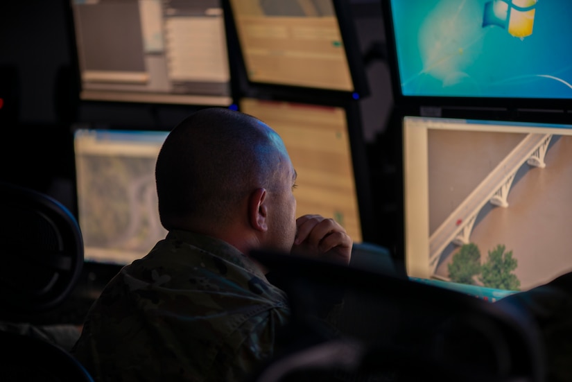 An airman works amid an array of computer monitors.