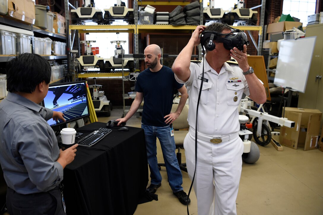 A sailor and two other men work with artificial intelligence devices.