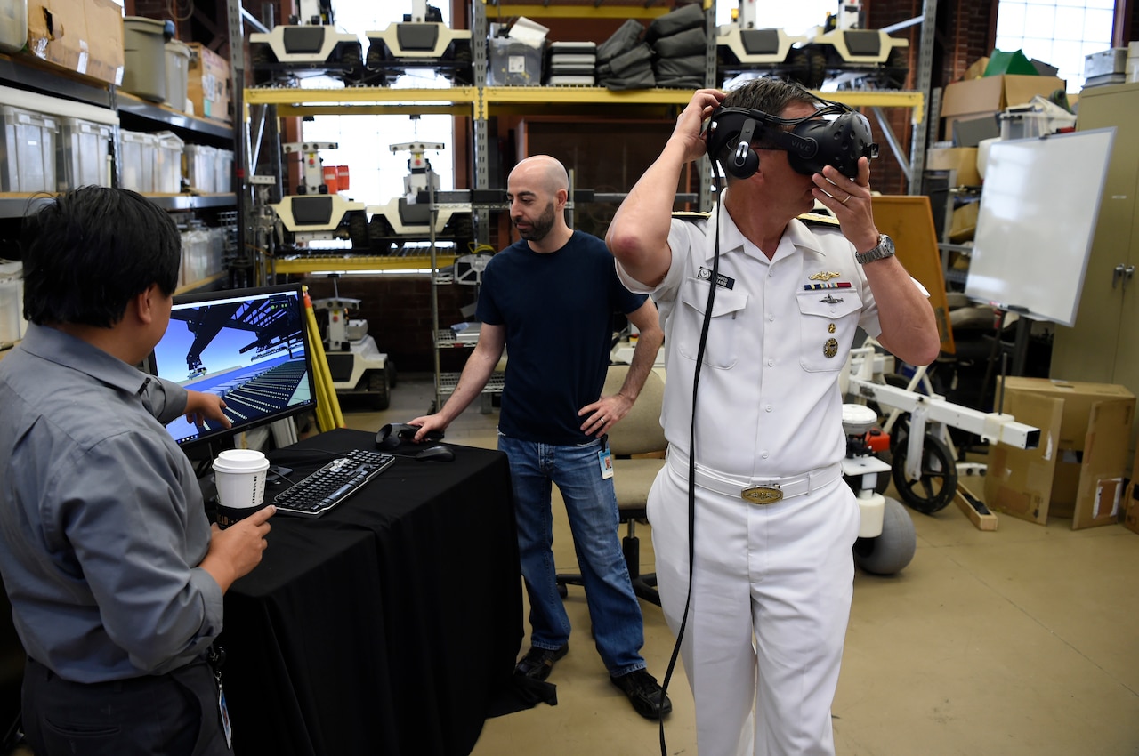 A sailor and two other men work with artificial intelligence devices.