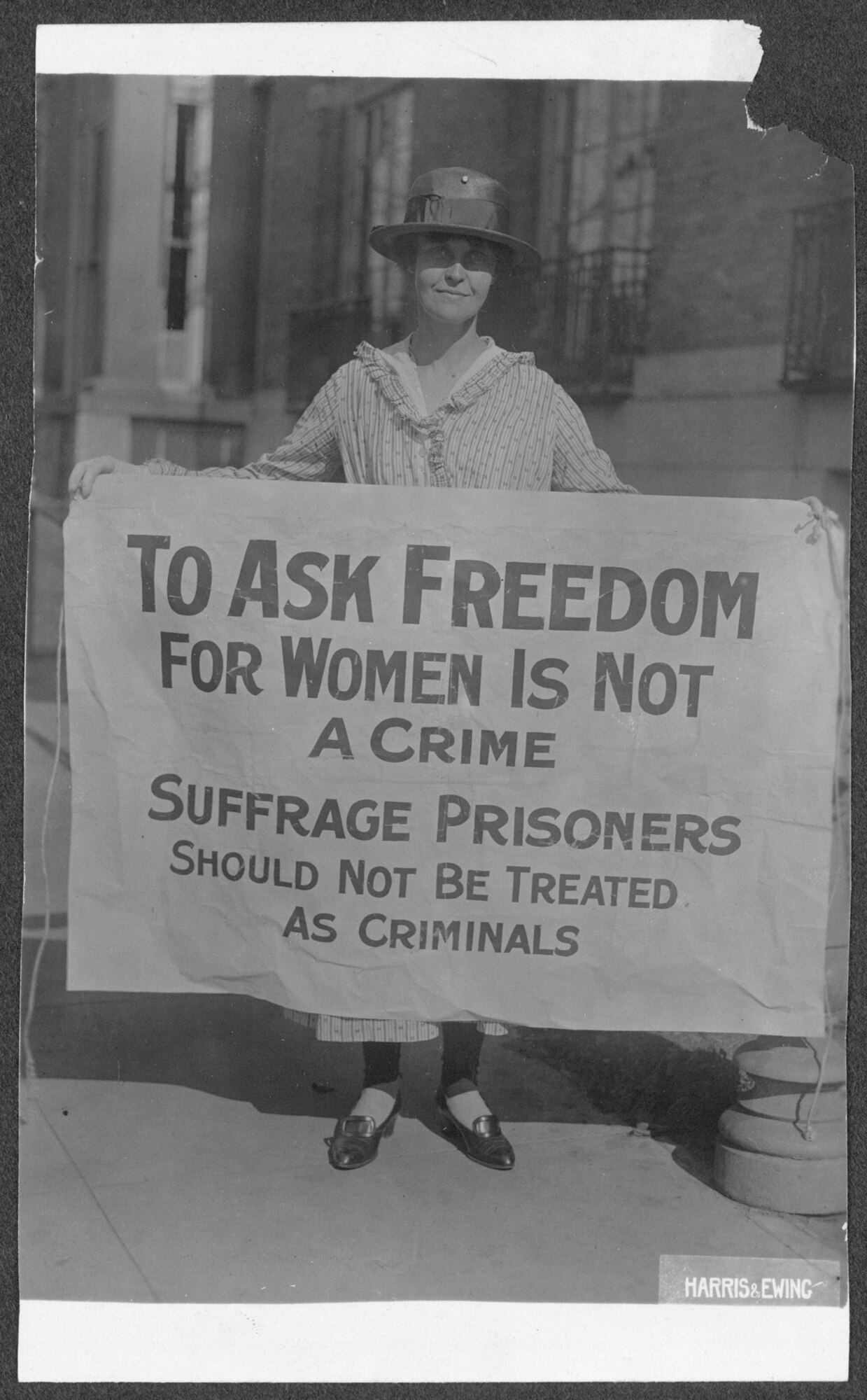 photograph from 1917 of woman during womans suffrage movement named Mary Winsor holding up a sign in protest. Sign reads as following   To ask freedom for women in not a crime