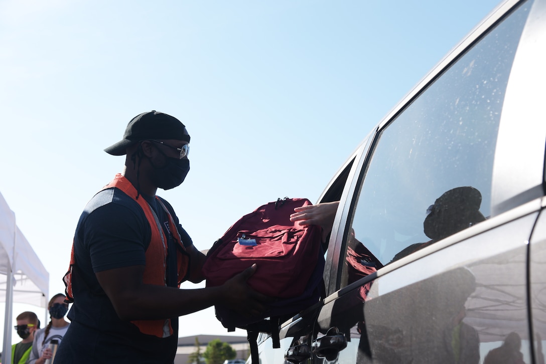 Senior Airman Mondrell Mincey, a 28th Logistics Readiness Squadron decentralized materials system technician, hands a backpack to a patron at Ellsworth Air Force Base, S.D., Aug. 15, 2020. The Back2School Brigade received over 400 backpacks and more than $2,000 worth of school supplies through donations from the local community. (U.S. Air Force photo by Senior Airman Thomas Karol)