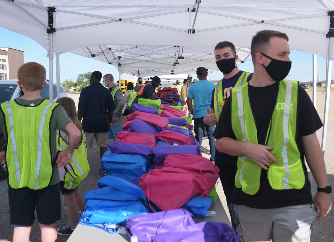 Volunteers from the Back2School Brigade wait to give school supplies to parents at Ellsworth Air Force Base, S.D., Aug. 15, 2020. The Back2School Brigade typically hosts the event inside the Pride Hangar, but due to the 2019 Novel Coronavirus (COVID-19), the event changed to a drive-through event where volunteers handed out school supplies and minimized contact between people. (U.S. Air Force photo by Senior Airman Thomas Karol)