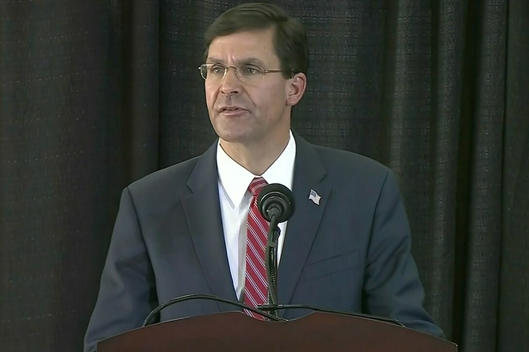 A man stands at a microphone on a lectern.