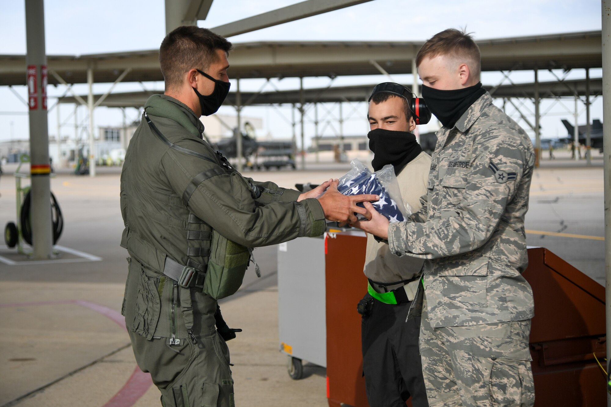 A pilot hands off sealed American flags to Airmen.