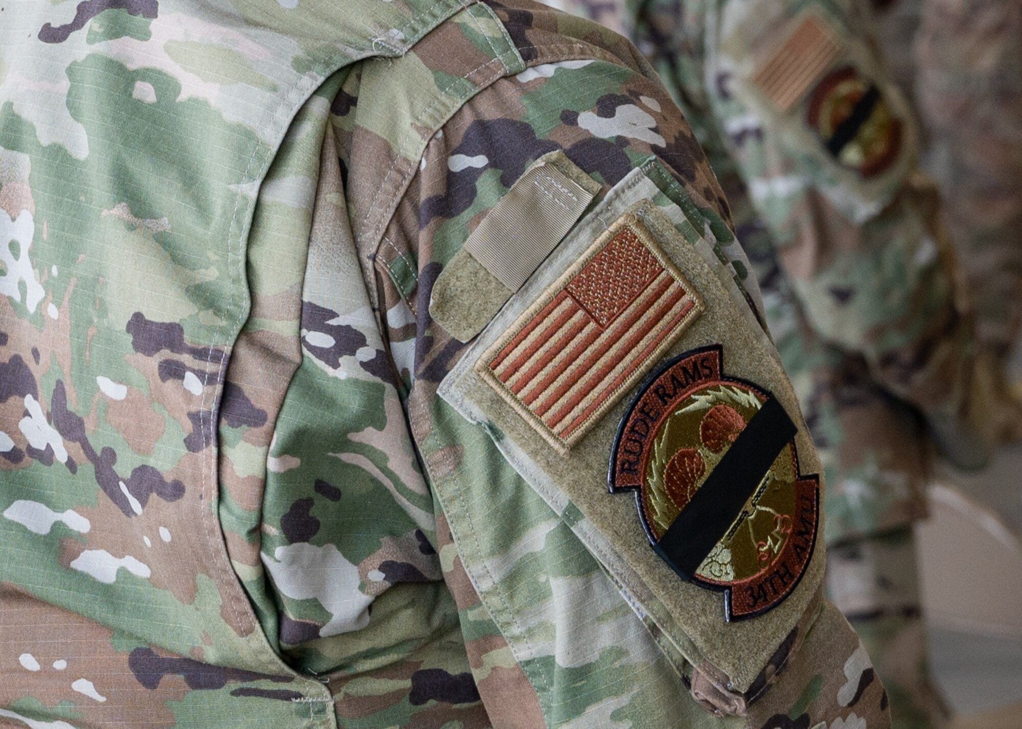 A picture of uniform personnel wearing a modified unit patch to commemorate a fallen Airman.