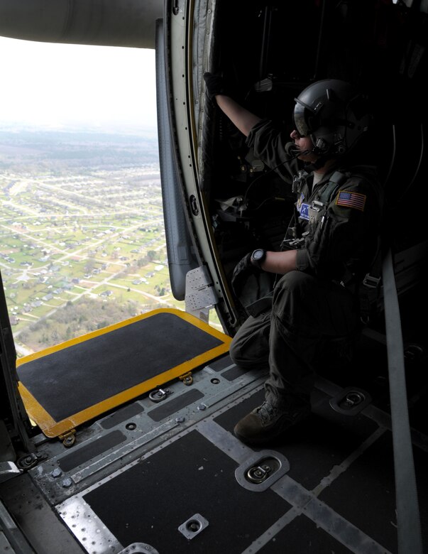 a man kneels looking our of an aircraft