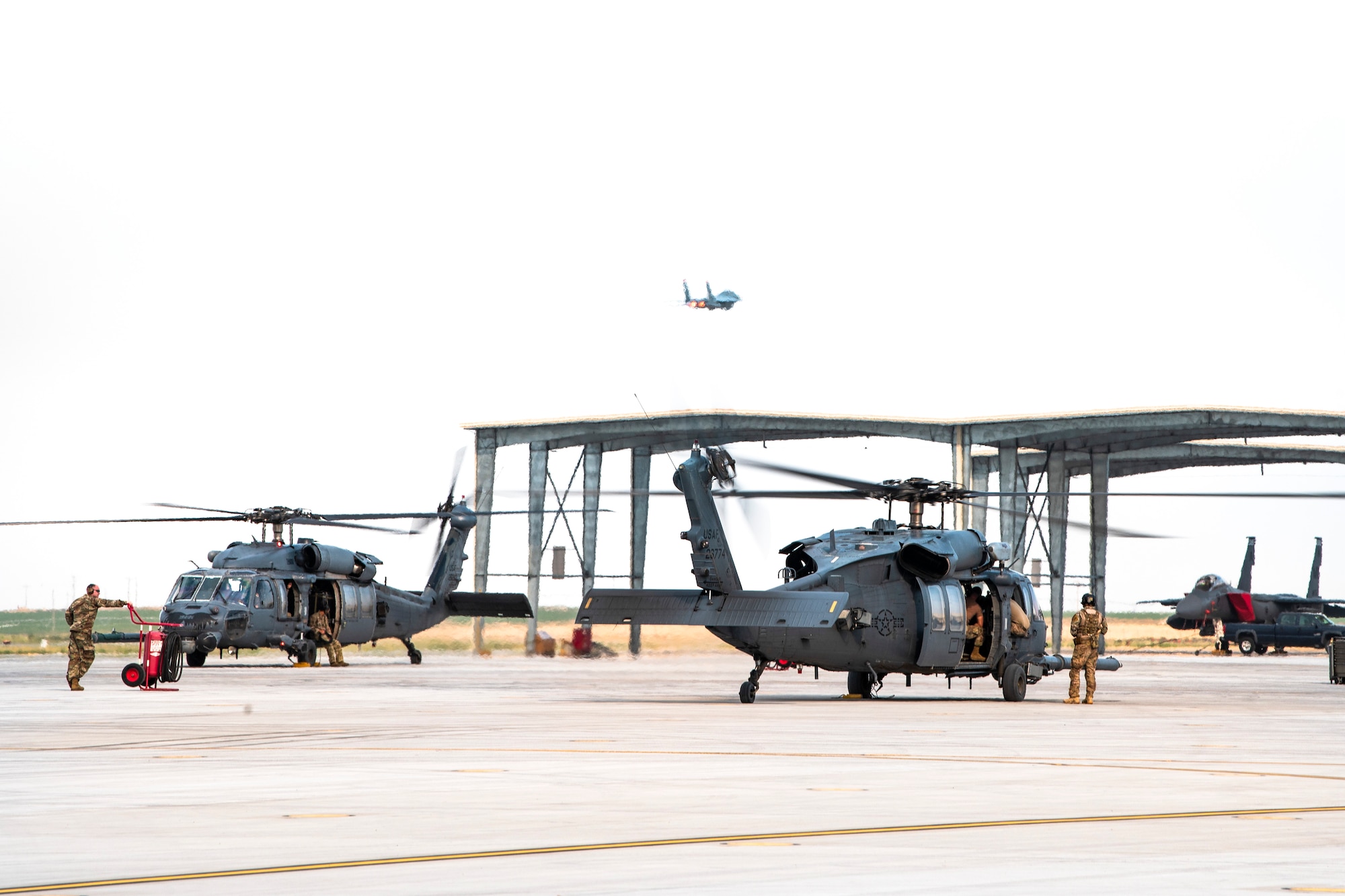 U.S. Air Force F-15E strikes eagles take-off while three HH-60G Pave Hawks standby Aug. 17, 2020, at Mountain Home Air Force Base, Idaho. Both airframes are participating in Gunfighter Flag 20-1, which aims to hone joint and multi-national armed forces to become more agile and lethal. (U.S. Air Force photo by Airman 1st Class Andrew Kobialka)