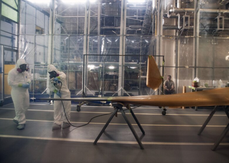 Staff Sgt. Alex Poteet (left), Aircraft Structural Maintenance Craftsman 374th Maintenance Squadron Fabrication Shop, and Airman 1st Class Isaiahlee Elizardo (right), Aircraft Structural Maintenance Journeyman 374th Maintenance Squadron Fabrication Shop, apply a coat of paint primer to a CV-22 blade inside of a Retractable Painter Containment System at Yokota Air Base, Japan, on August 12, 2020.