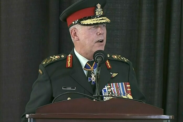 A man in a Canadian uniform stands at a microphone on a lectern.
