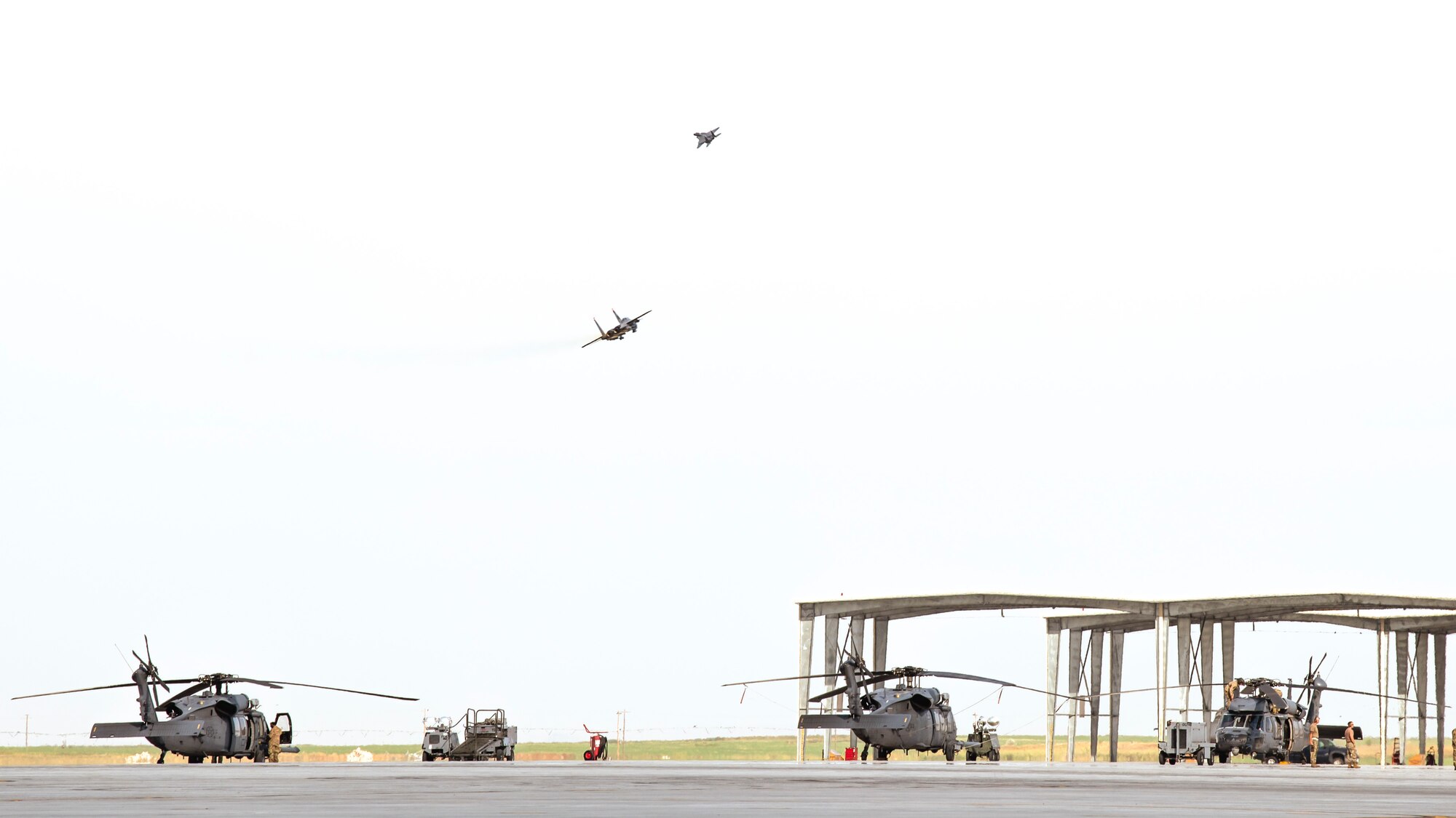 U.S. Air Force F-15E strikes eagles take-off while three HH-60G Pave Hawks standby Aug. 17, 2020, at Mountain Home Air Force Base, Idaho. Both airframes are participating in Gunfighter Flag 20-1, which aims to hone joint and multi-national armed forces to become more agile and lethal. (U.S. Air Force photo by Airman 1st Class Andrew Kobialka)