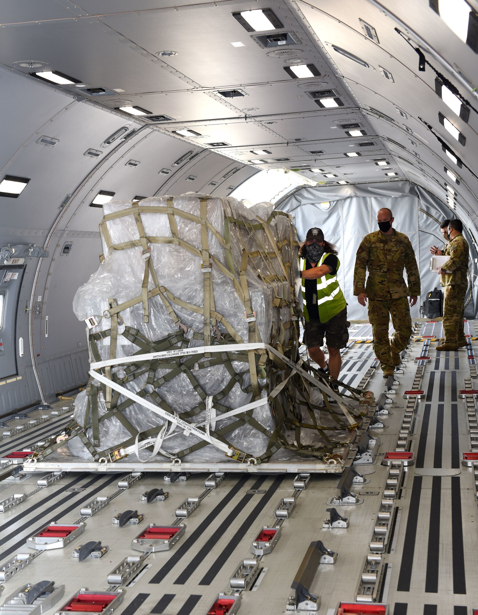 A civilian from the 727th Air Mobility Squadron loads cargo onto a KC-46A Pegasus as a crew chief from McConnell Air Force Base, Kansas, helps guide him at RAF Mildenhall, England, Aug. 18, 2020. Aircrew and crew chiefs, along with two KC-46s, spent time here to train alongside KC-135 Stratotanker aircrew. The KC-46 has undergone extensive testing this past year, and the successful completion of its first aeromedical evacuation in July 2020 represents a significant milestone in the aircraft’s ability to demonstrate one of its three mission sets: aerial refueling, airlift and aeromedical evacuation. (U.S. Air Force photo by Karen Abeyasekere)