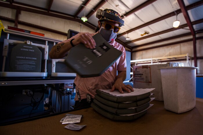 A Non-Destructive Testing Equipment team member stacks tested hard armor body inserts with foam padding before loading into a shipping container at Cannon Air Force Base, N.M., Aug. 4, 2020. Plates containing no signs of damage are considered serviceable and are good for future use while plates with slight to major damage are repurposed for training or destroyed. (U.S. Air Force photo by Staff Sgt. Luke Kitterman)