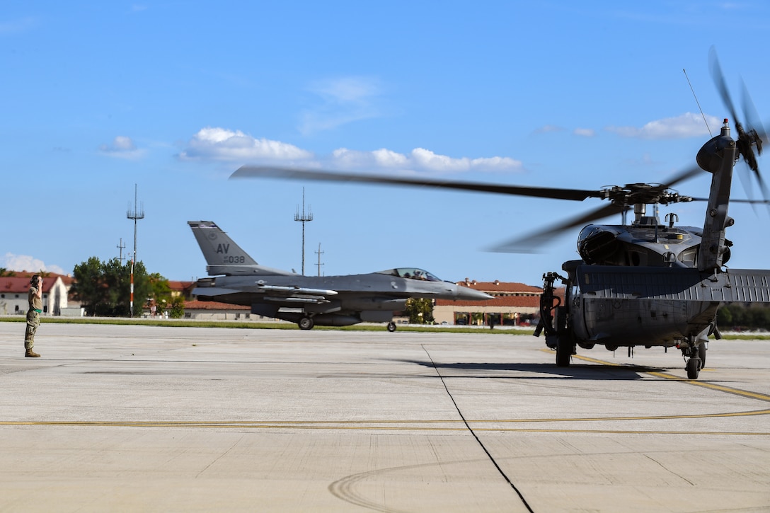 An Airman with the 56th Helicopter Maintenance Unit salutes as an HH-60G Pave Hawk helicopter prepares to take off at Aviano Air Base, Italy, Aug. 19, 2020. The primary mission of the HH-60G is to conduct day or night personnel recovery operations into hostile environments to recover isolated personnel. The 56th RQS provides a rapidly-deployable, worldwide combat rescue and reaction force response utilizing the HH-60G. (U.S. Air Force photo by Airman 1st Class Thomas S. Keisler IV)
