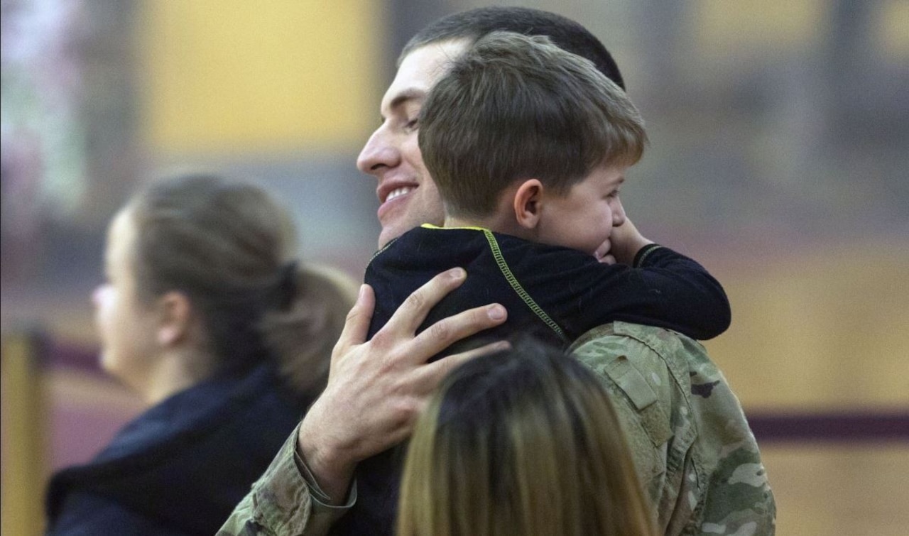 A soldier hugs a small child.