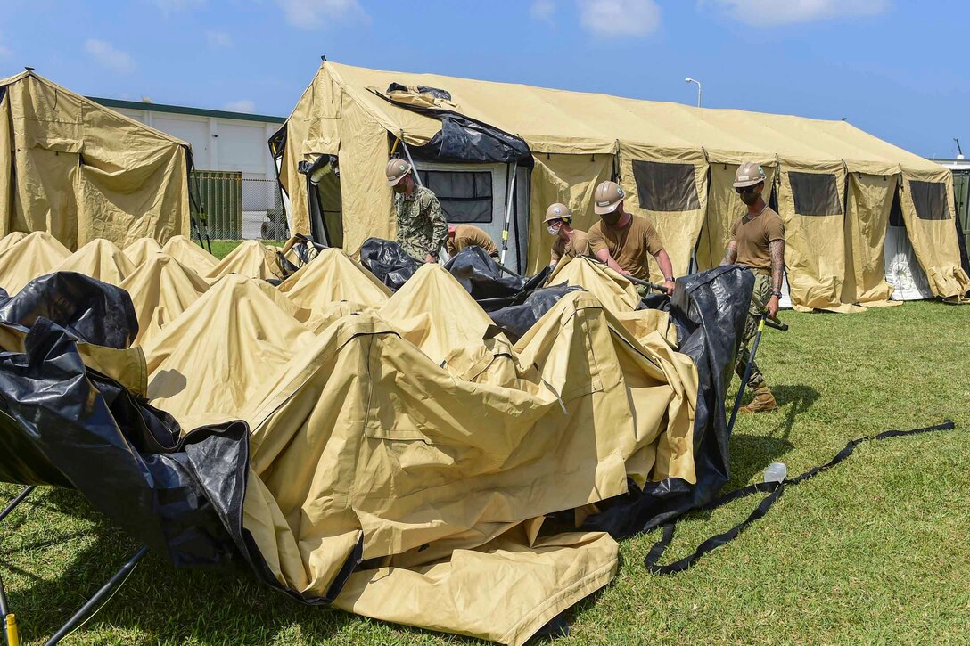 A group of sailors set up a tent.