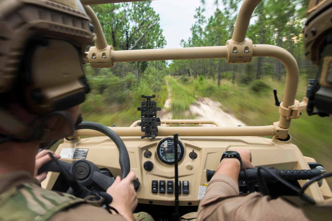 Two airmen drive in a military vehicle.