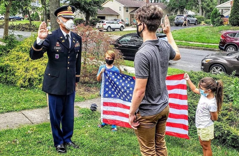 Future Soldier Ronald Kaszian Sauerbrey receives his Oath of Enlistment from company commander Capt. Mehmet Bahadir, while his younger siblings hold the American flag behind them.