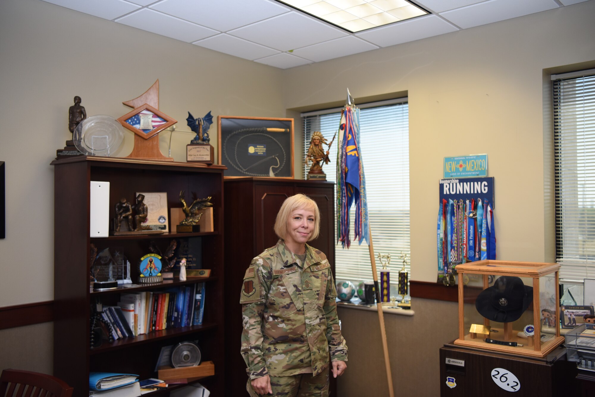 U.S. Air Force Chief Master Sergeant Casy Boomershine, 17th Training Wing command chief, poses next to her favorite awards at Norma Brown building on Goodfellow Air Force Base, Texas, Aug. 5, 2020. One of her most prized awards is a bullwhip she earned for “whipping” a B-1 Isochronal Inspection shop into shape. (U.S. Air Force photo by Airman 1st Class Ethan Sherwood)