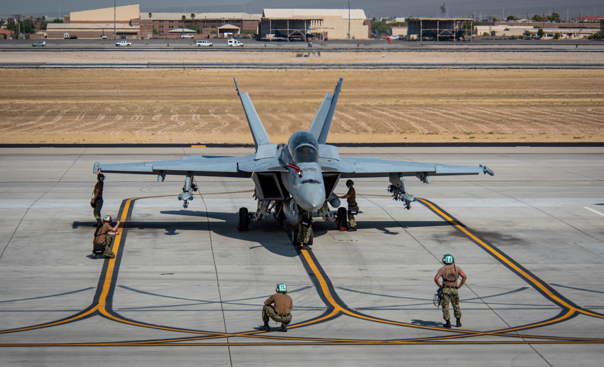 Aircraft sits on flight line surrounded by sailors.