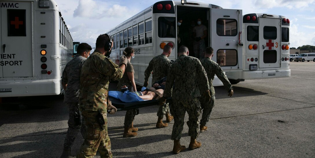 Airmen and Seamen move a patient into a medical transport bus at Joint Base Andrews, Md., Aug. 13, 2020. Medical staff work together with other units and services to ensure they provide the best quality care possible for patients. (U.S. Air Force photo by Airman 1st Class Spencer Slocum)