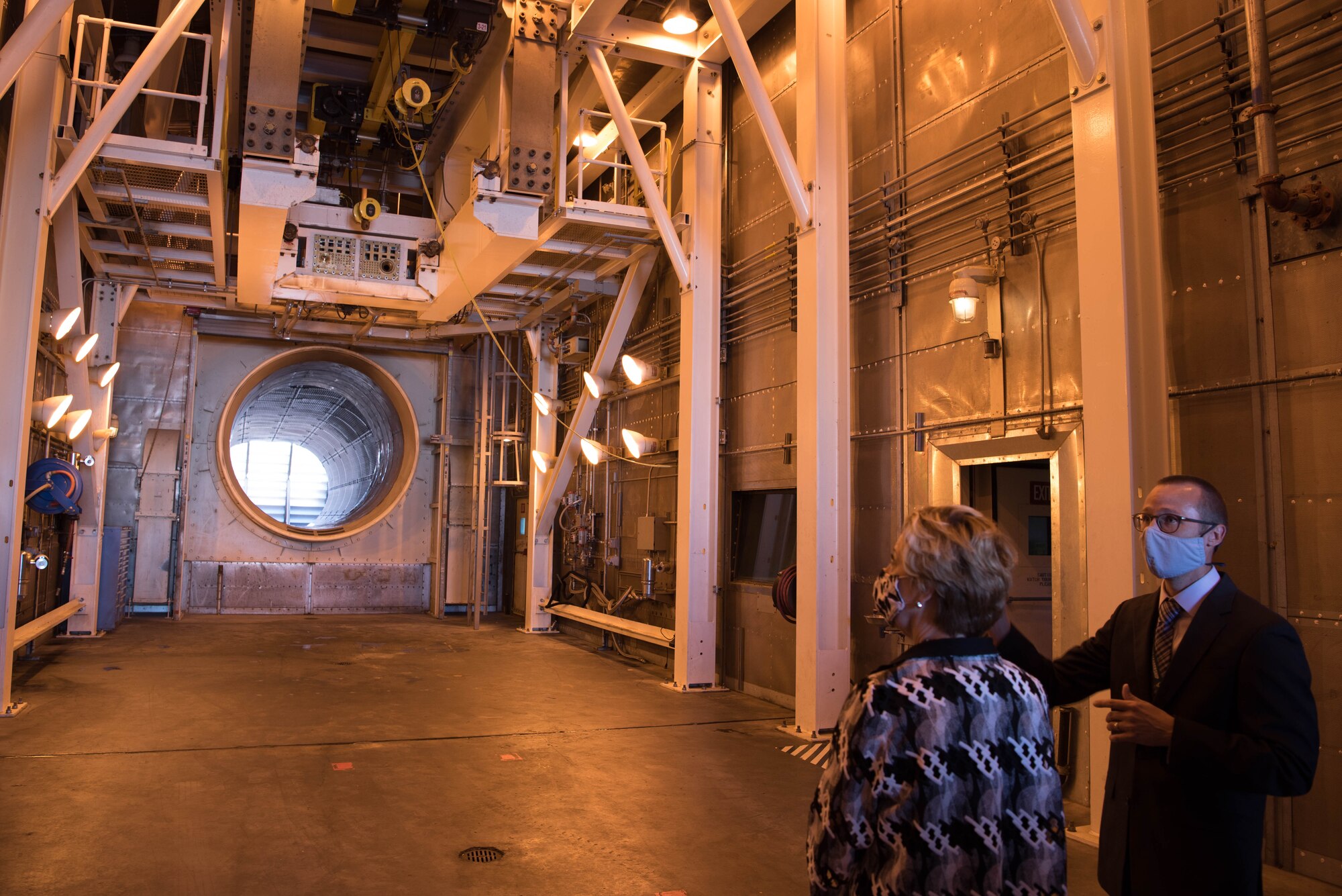 Two people looking at empty jet engine test cell.